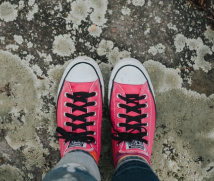 Pinke Converse Schuhe mit schwarzen Schnürsenkeln auf der Straße