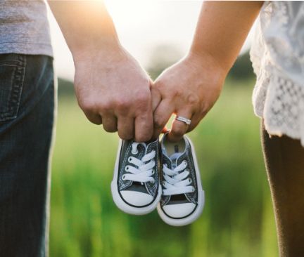 Hände eines Paares mit Converse Schuhen in Babygröße