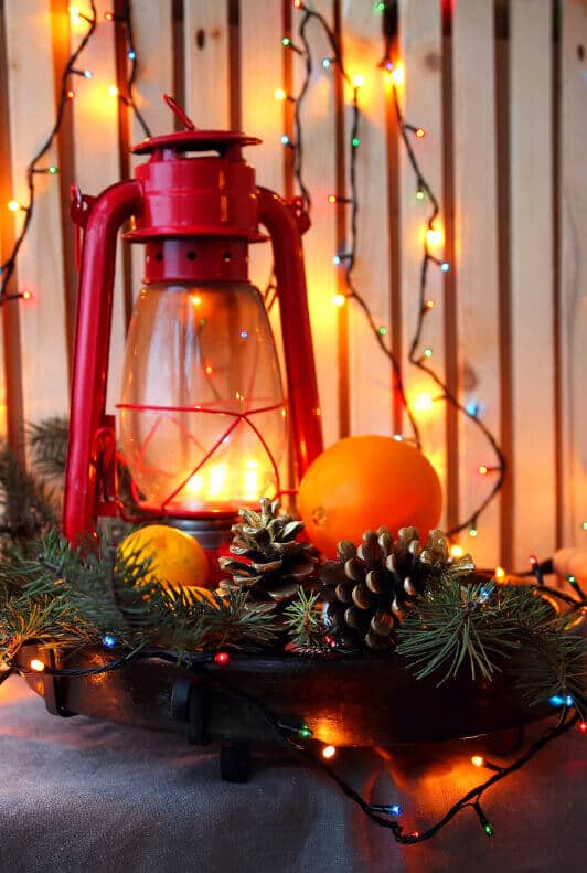 Weihnachtsdekoration mit Sturmlampe, Tannenzapfen und Lichterkette