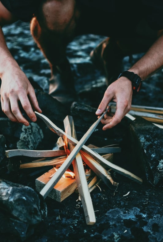 Mann macht ein Lagerfeuer mit Holz