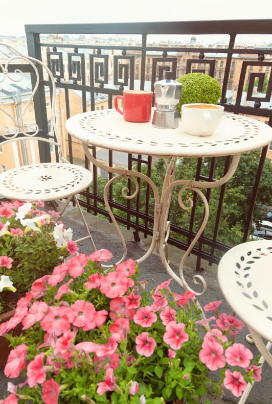 Kleiner Balkon mit Bistro-Set Blumen und Kaffeetassen 